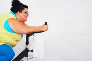 Leptina e Obesità: Donna obesa che fa cyclette