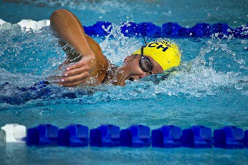 Atleta donna nuota a stile libero con cuffia gialla