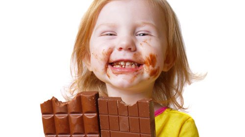 Bimba che mangia due grosse barrette di cioccolato